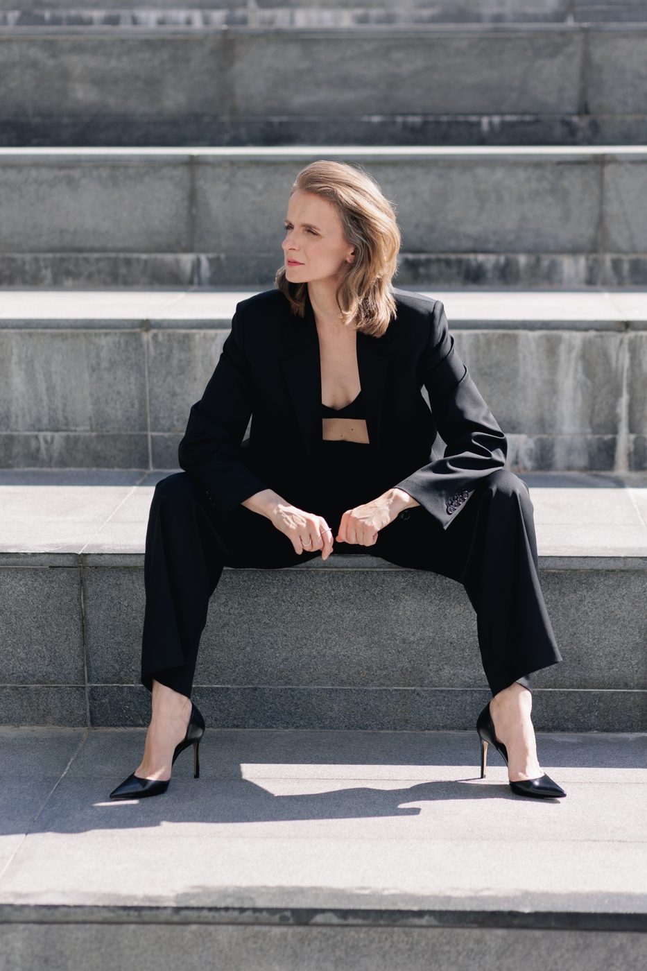 Monika Valkunaite in a black suit on stone steps
