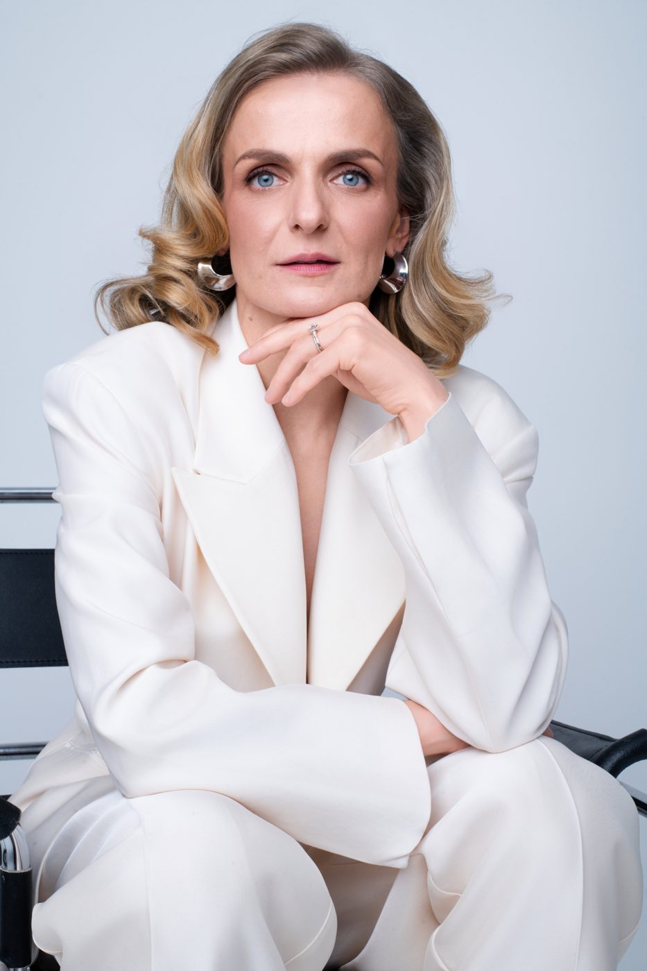 Monika Valkunaite seated in a white suit